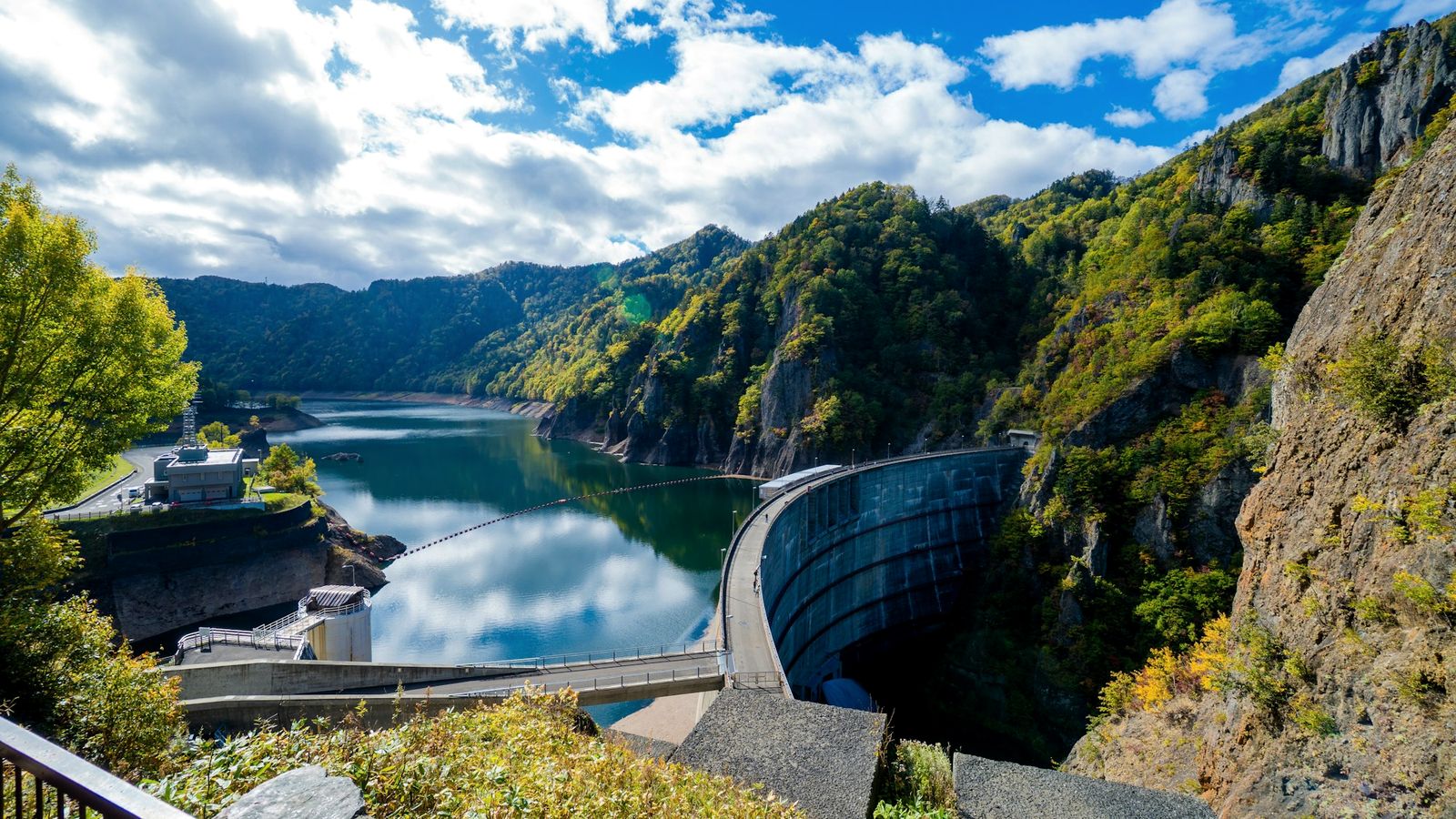 A curved concrete dam holding back a mountain reservoir