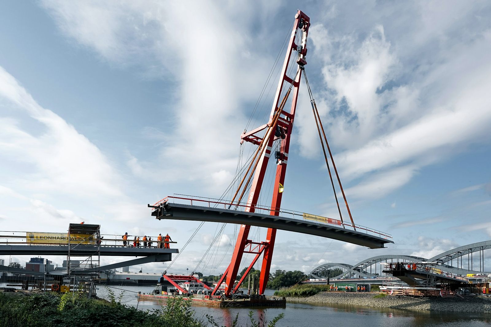 A floating crane lifting a new bridge section into place over a river